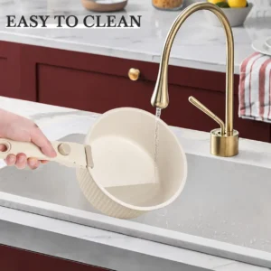 cream-detachable-handle-saucepan-easy-to-clean Cream ribbed saucepan with a detachable handle being rinsed under a kitchen faucet.