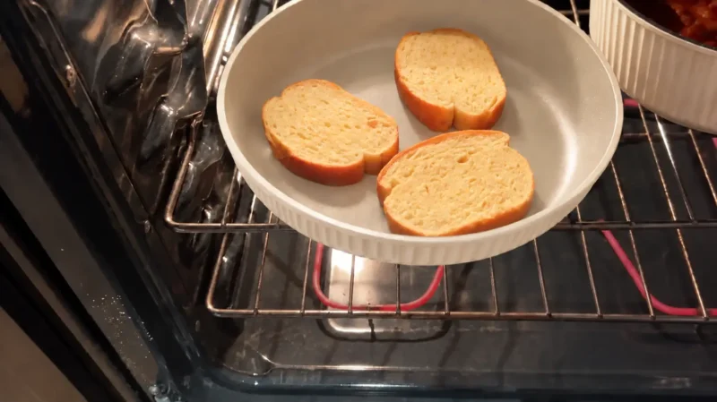 cream-frying-pan-in-oven Cream ribbed frying pan without its handle, holding three bread slices inside an oven.